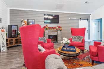 a living room with red chairs and a fireplace