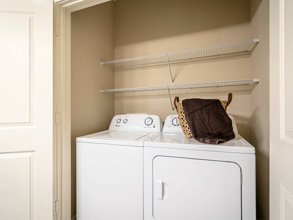 an empty laundry room with a washer and dryer and a basket on top