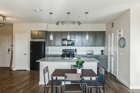 A kitchen with a table and chairs in front of it.