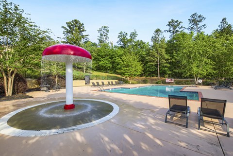 a fountain with a red umbrella next to a pool