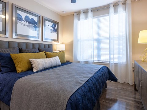 A bedroom with a bed, pillows, and a lamp.