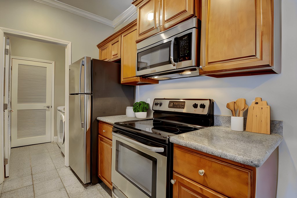 A kitchen with a stove, refrigerator, and microwave.