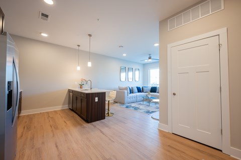 A kitchen with a refrigerator, a counter, and a dining table with chairs.