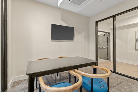 A conference room with a table, chairs, and a television on the wall.