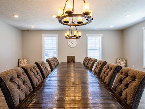 a long dining room table with chairs and a clock on the wall