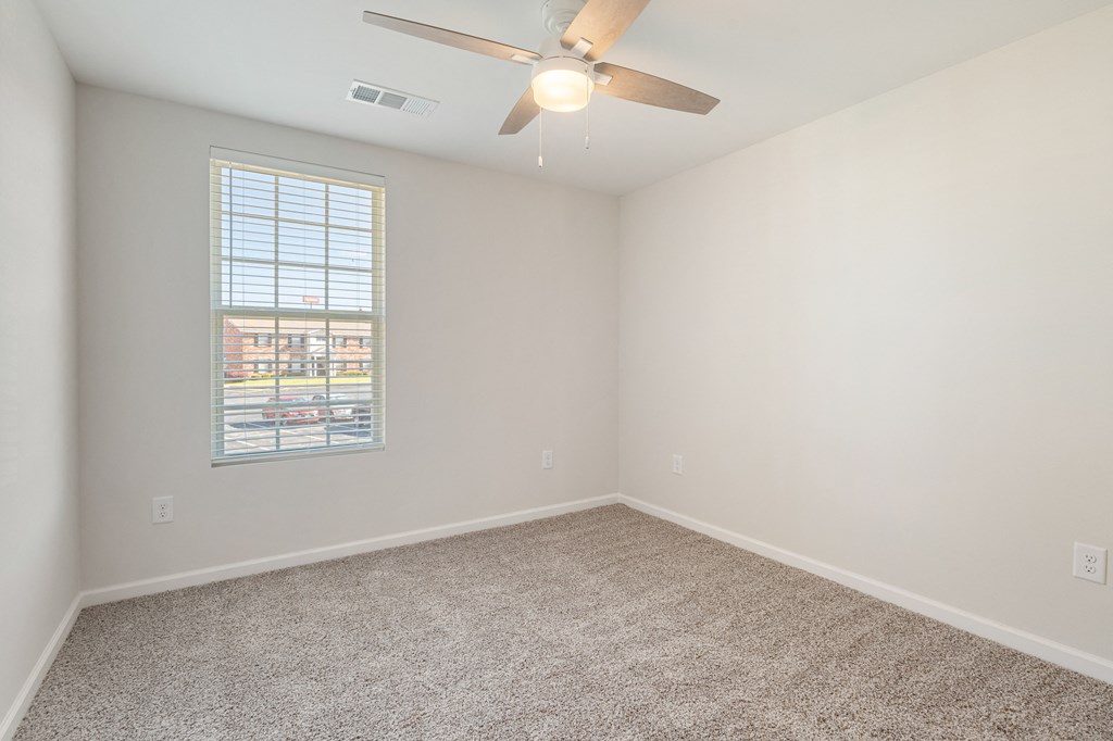 an empty room with a ceiling fan and a window