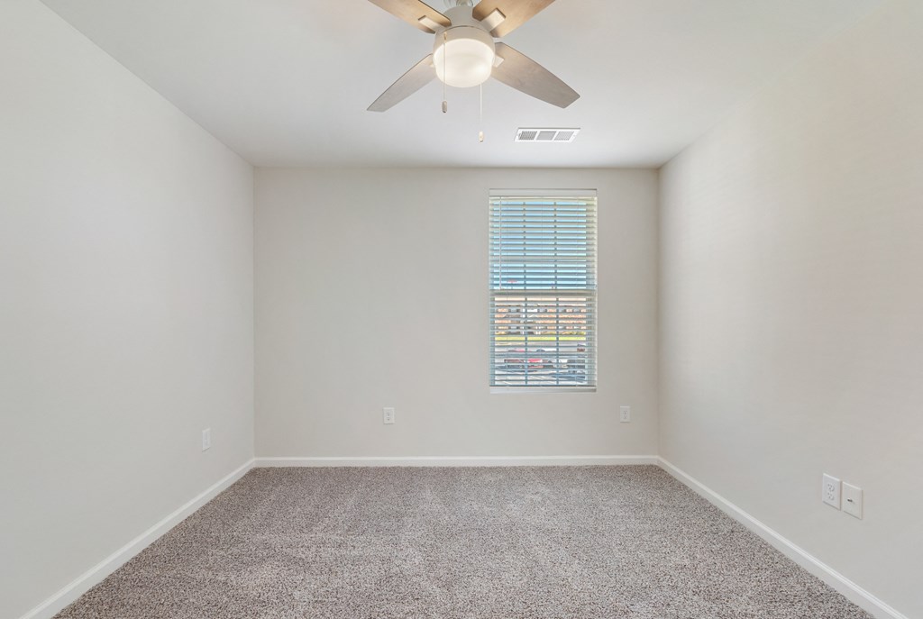 an empty room with a ceiling fan and a window