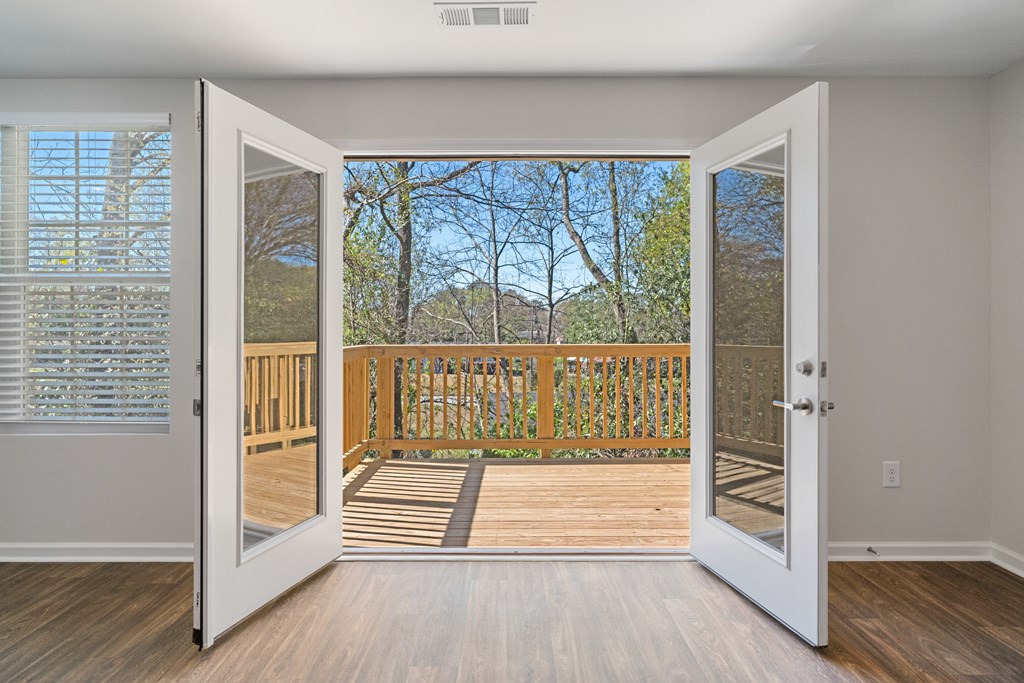 an open door leading to a balcony with a view of the woods