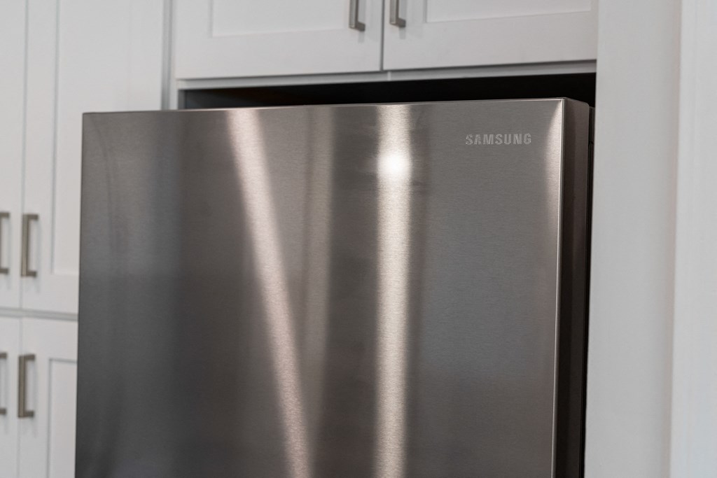a stainless steel refrigerator in a kitchen with white cabinets