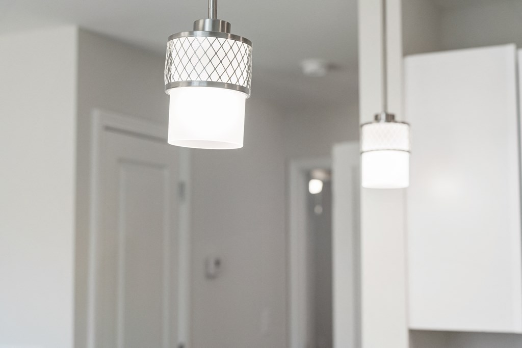 three lights hanging from a ceiling in a white kitchen