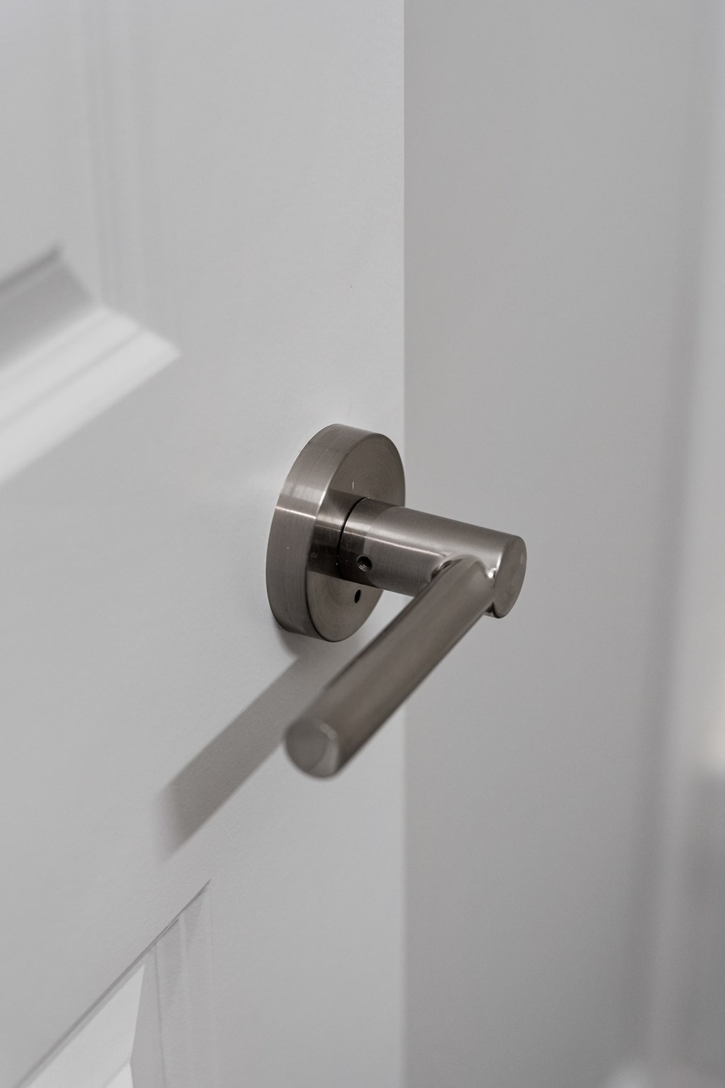 a door handle in a white door with a shadow on the wall