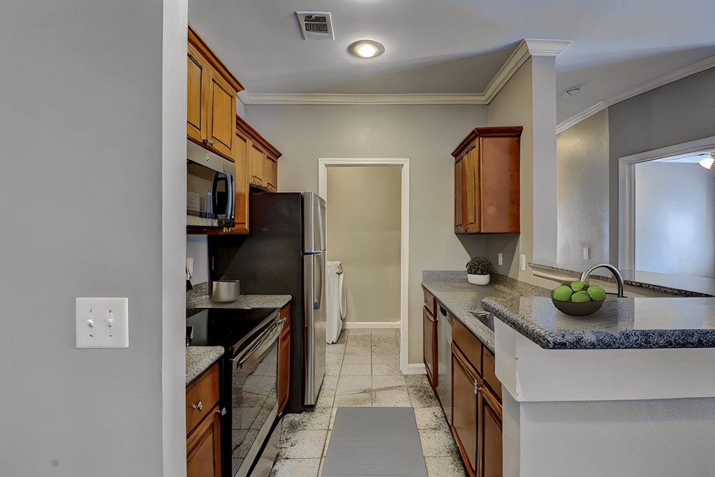 A kitchen with a black refrigerator and wooden cabinets.