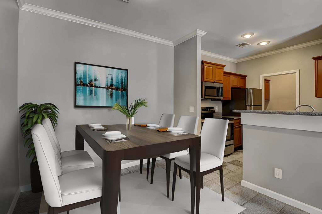 A dining room with a table set for two and a painting on the wall.