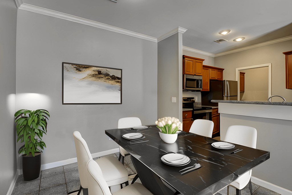 A dining room with a black table and white chairs.