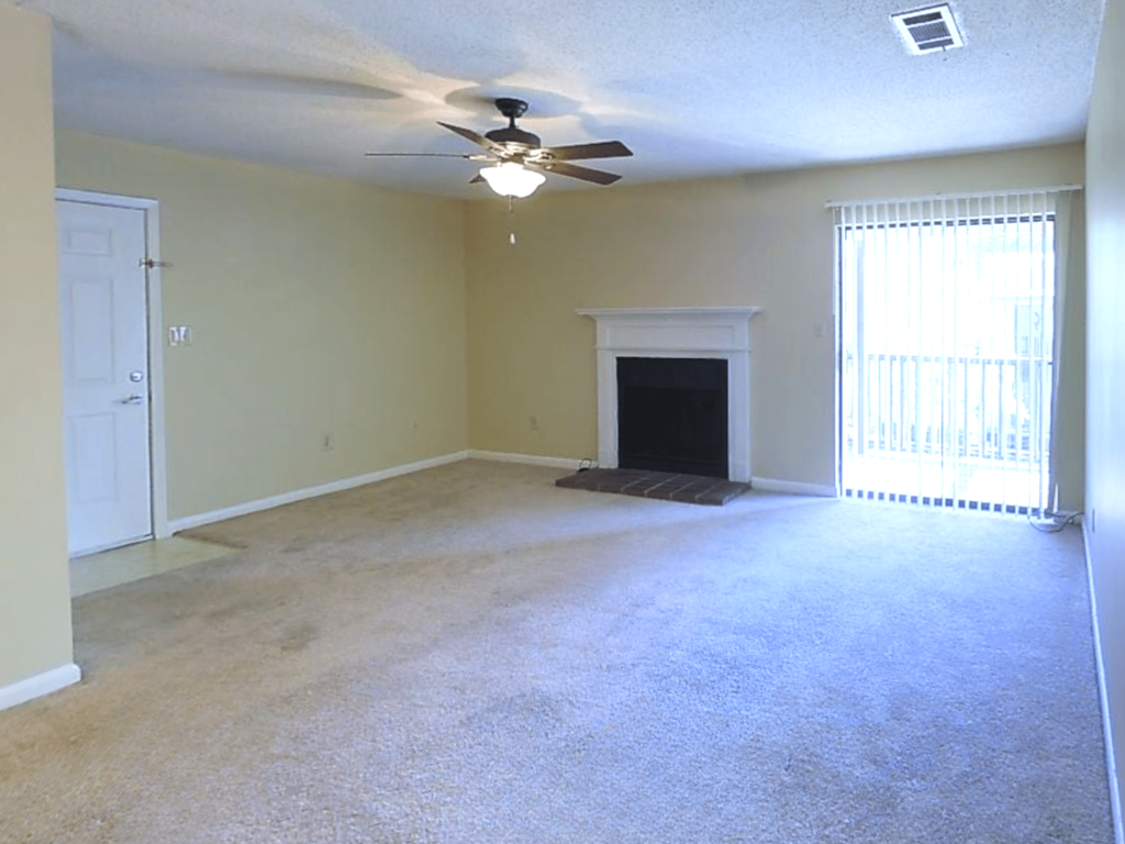an empty living room with a ceiling fan and a fireplace