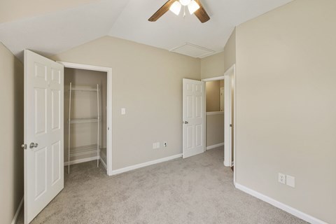 A room with a ceiling fan and two open doors.