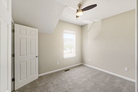 A room with a ceiling fan and a door.