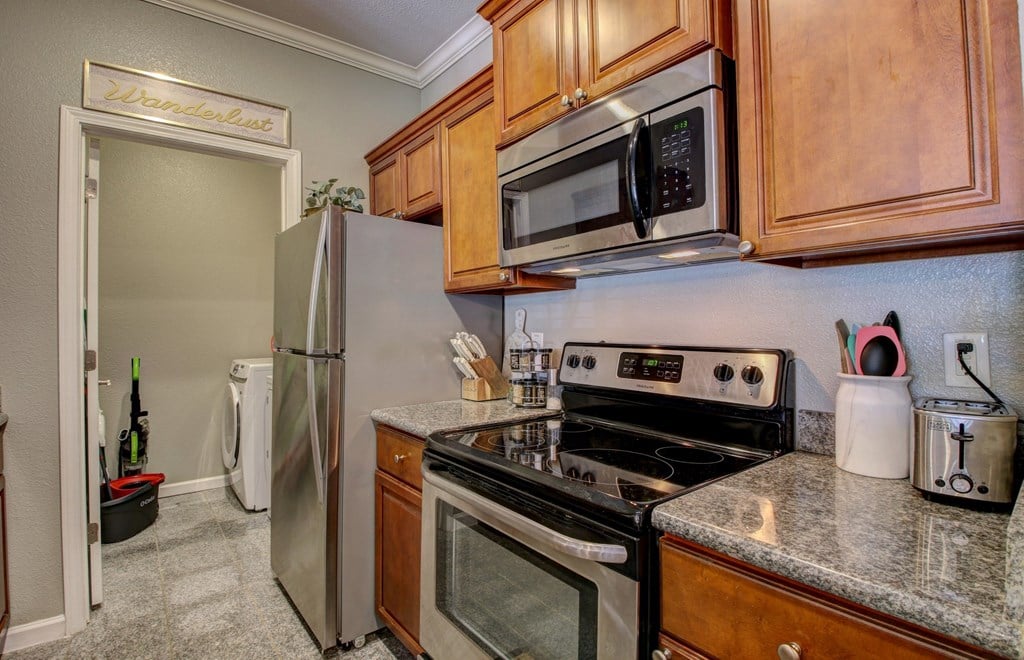 A kitchen with a stove, oven, refrigerator, and microwave.