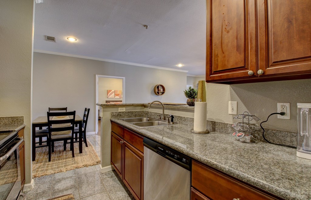 A kitchen with a sink, dishwasher, and a table with chairs.