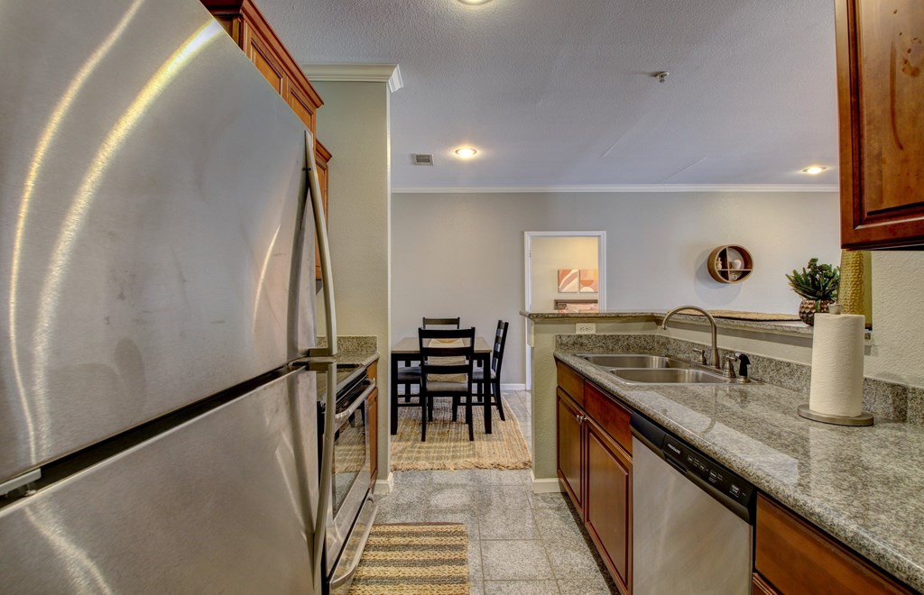 A kitchen with a stainless steel refrigerator and a dining table with chairs.