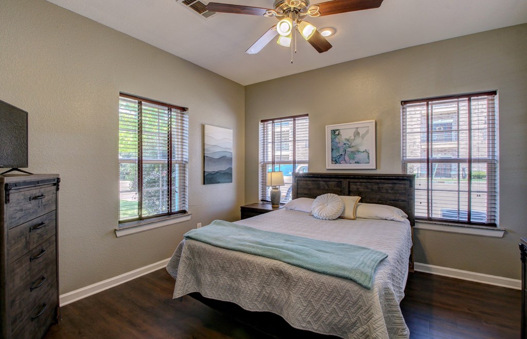 A bedroom with a bed, dresser, and a ceiling fan.