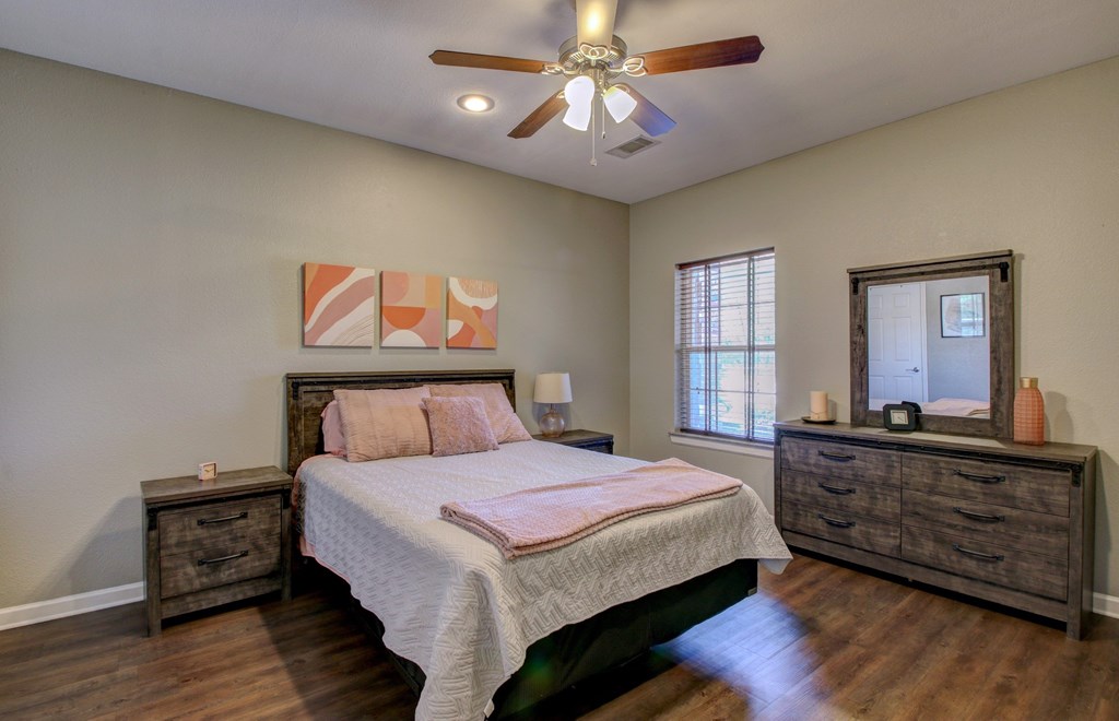 A bedroom with a bed, dresser, and mirror.