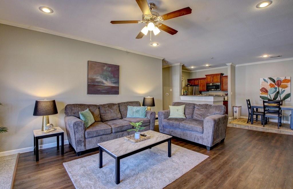 A living room with a grey couch, a coffee table, and a ceiling fan.