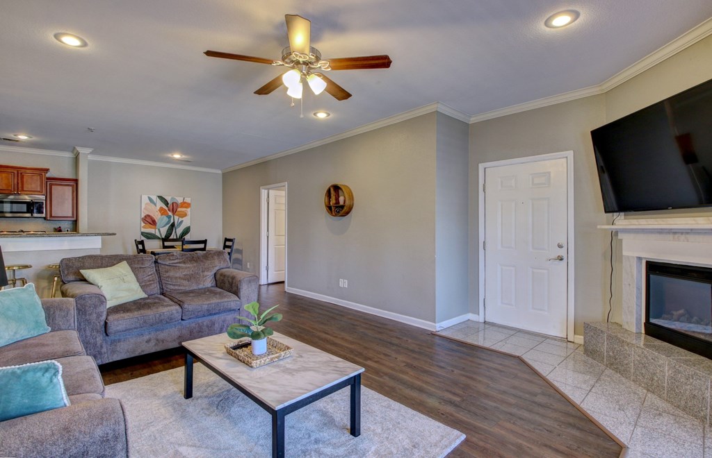 A living room with a grey couch and a ceiling fan.
