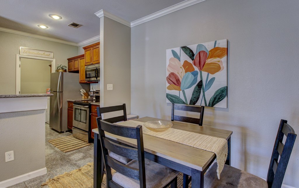 A kitchen with a table and chairs in front of a painting.