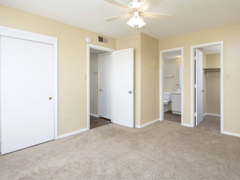 an empty living room with three doors and a ceiling fan