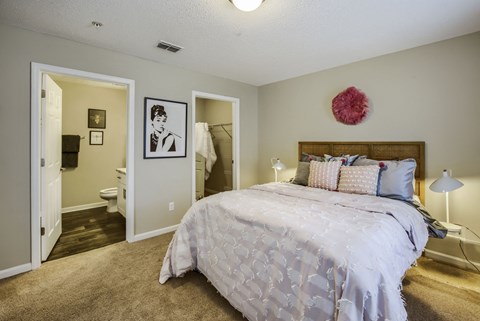 a bedroom with a large bed and a bathroom in the background