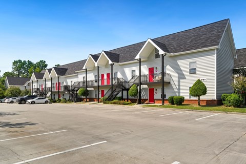 A parking lot in front of a building with red doors.