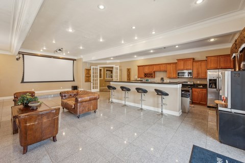a large kitchen and living room with a bar and a projector screen