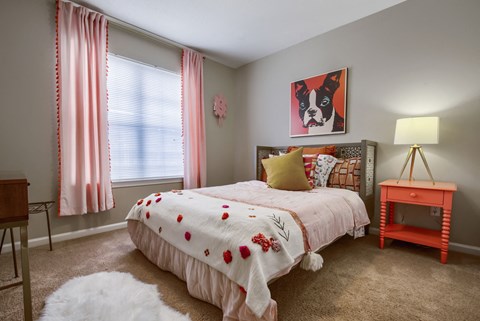 a bedroom with a bed and a nightstand with a lamp and a painting of a dog