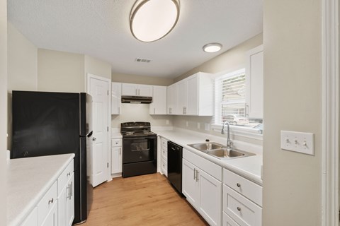 A kitchen with white cabinets and a black fridge.