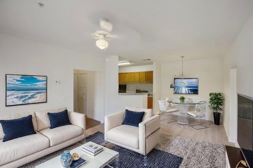 A living room with a white couch and a blue vase on the coffee table.