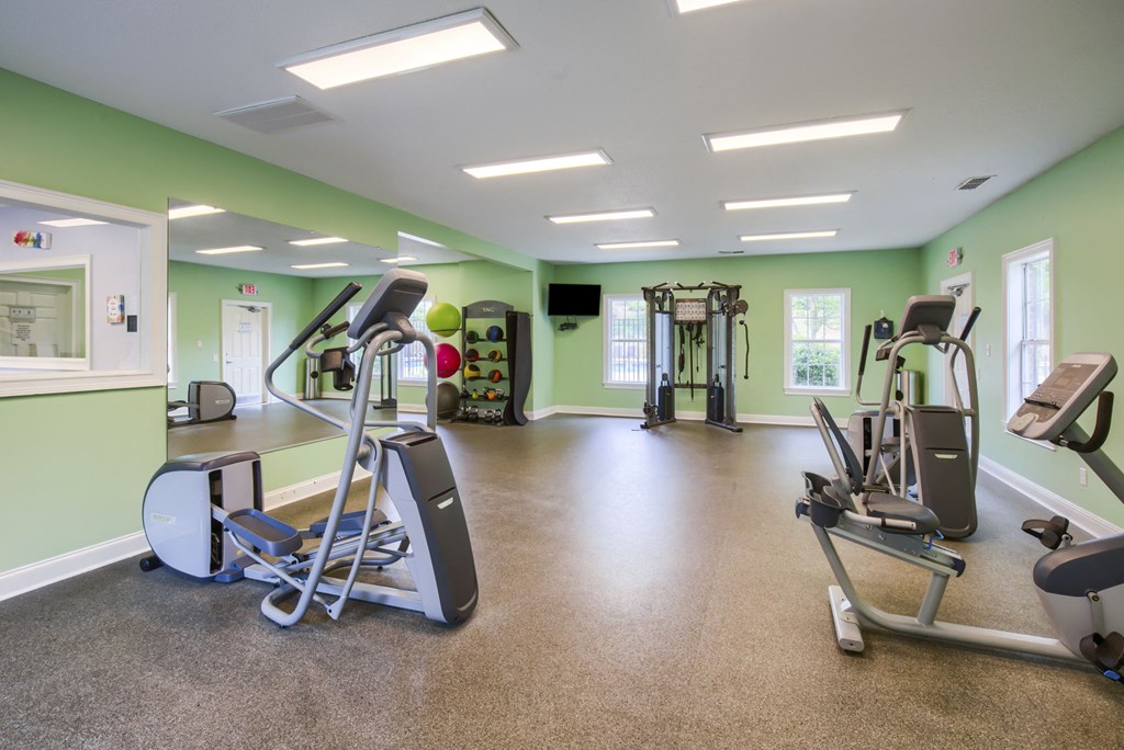 an exercise room with treadmills and other fitness equipment