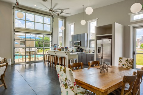 the kitchen and dining room with large windows and a wooden table