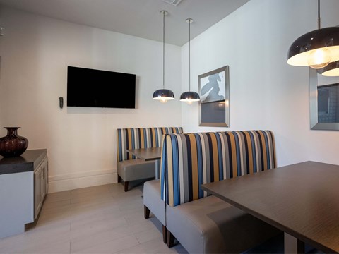A living room with a striped couch and a television mounted on the wall.