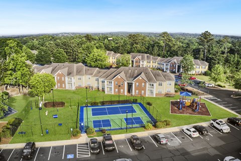 an aerial view of a tennis court and parking lot in front of a row of houses