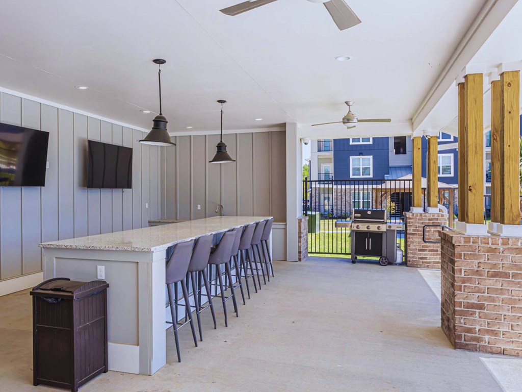 a long bar with chairs in a room with a grill