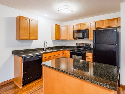 a kitchen with an island and black appliances and wooden cabinets