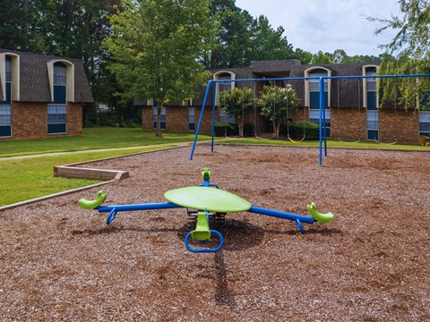 a playground with a swing set in front of a building