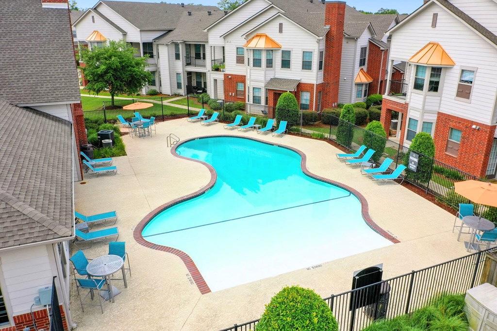 an aerial view of a large swimming pool with lounge chairs and umbrellas in front of