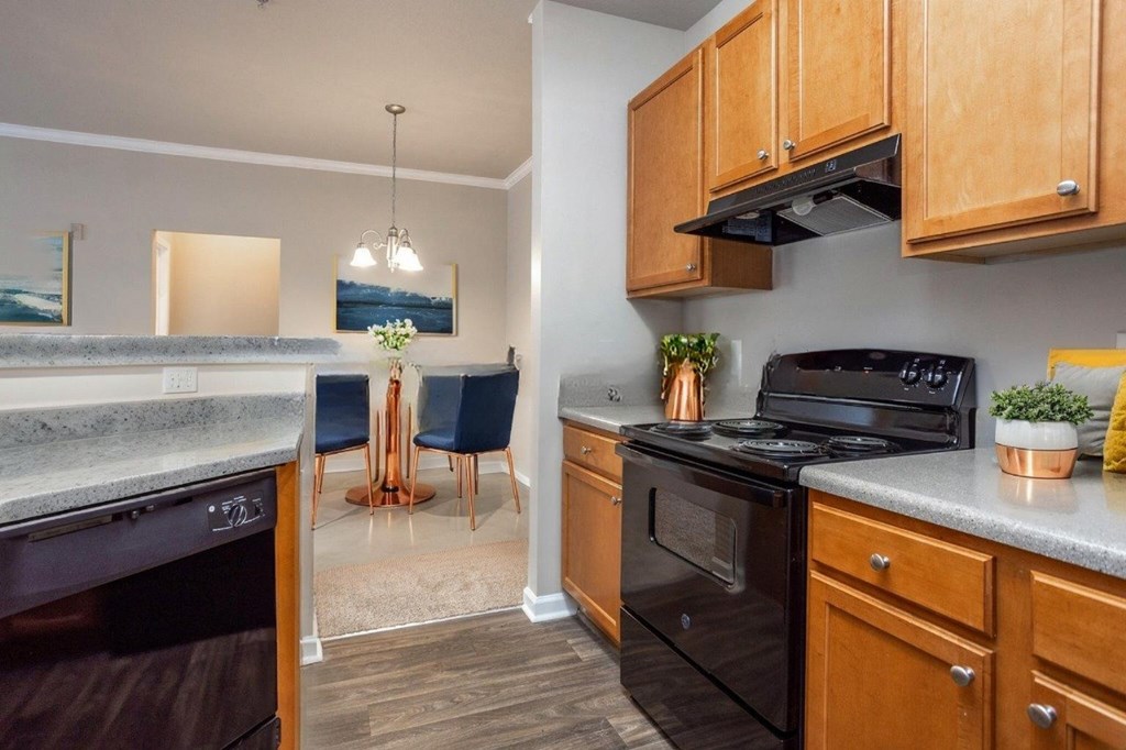 A kitchen with a black stove top oven and wooden cabinets.