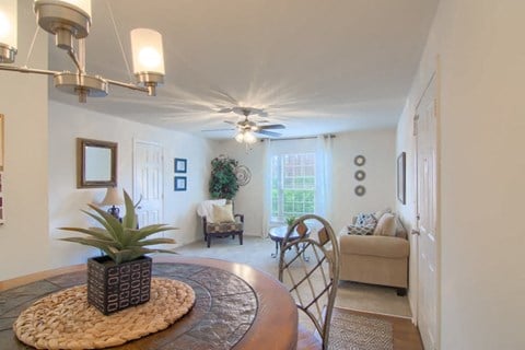 a living room with a round table and a ceiling fan