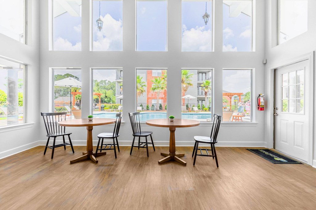 A dining room with a table and chairs in front of a large window.
