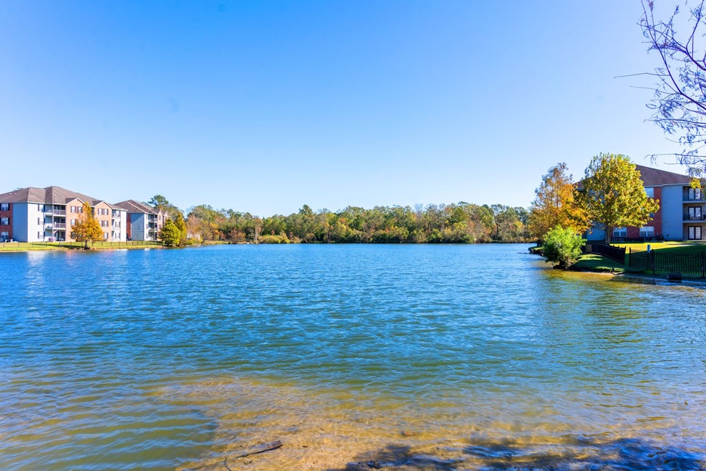 A serene lake with a row of buildings in the background.