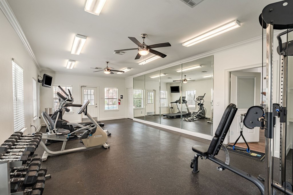 A spacious home gym with a variety of equipment including treadmills, weights, and a mirrored wall.
