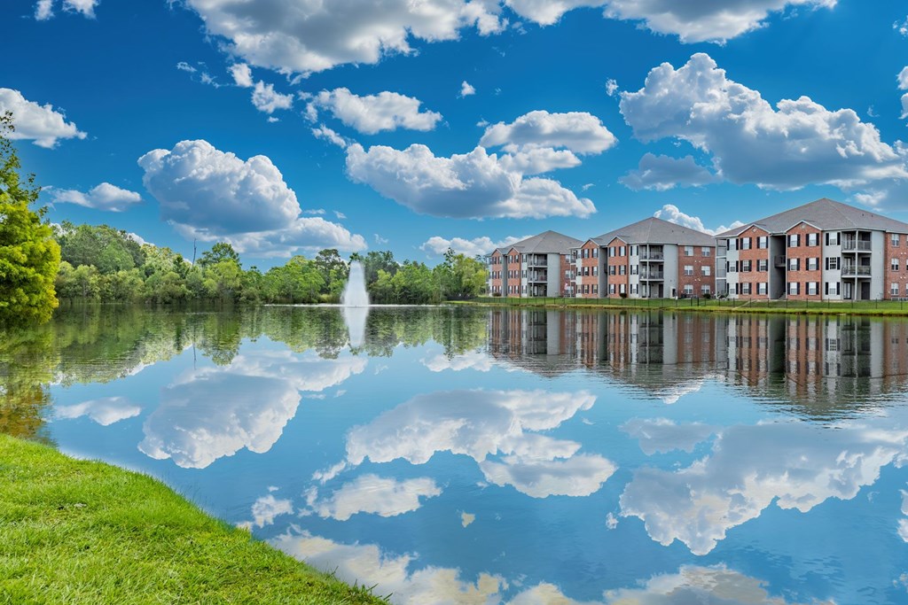 A serene lake with a building in the background and clouds in the sky.